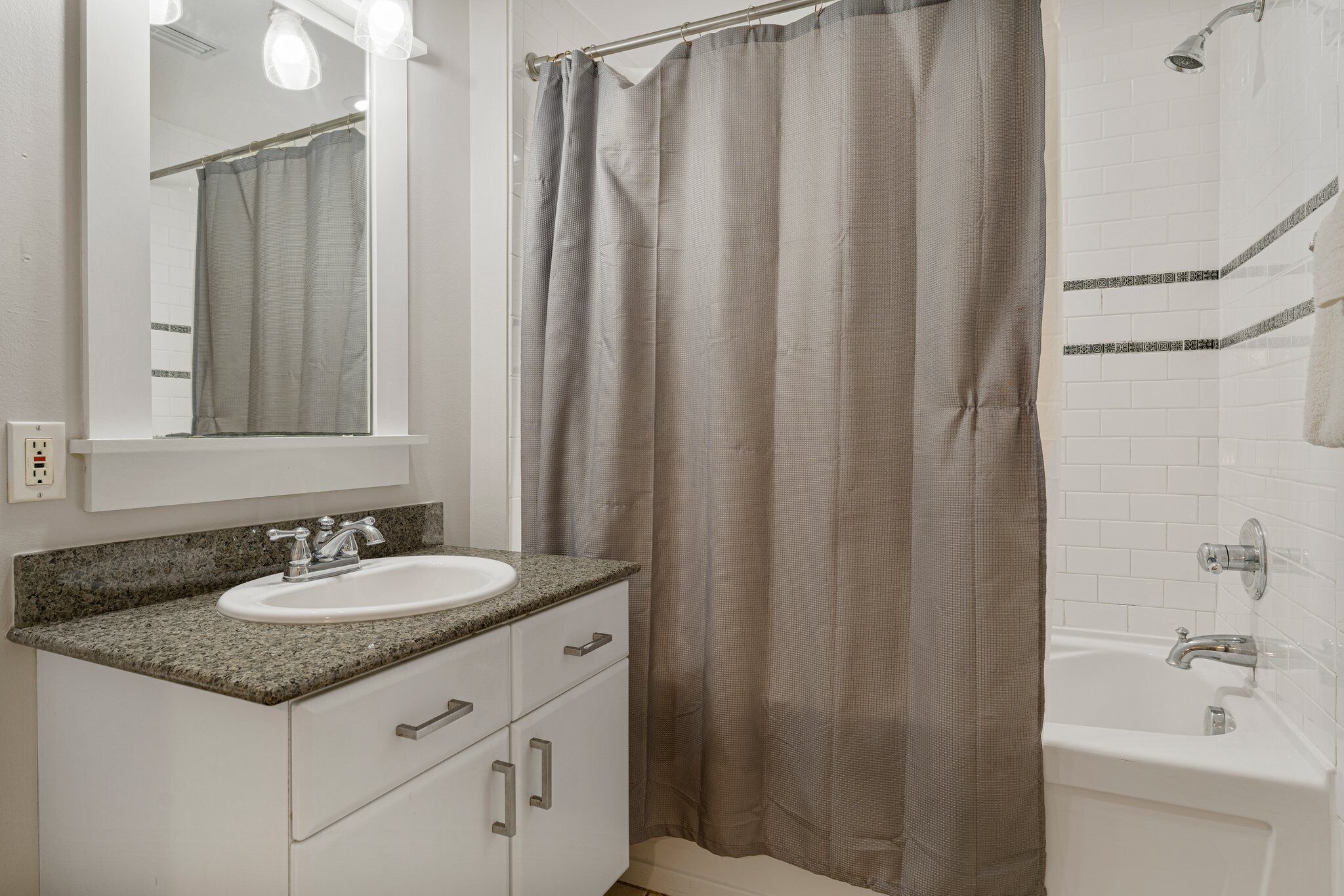 Un baño con lavamanos blanco, un espejo, cortina de ducha y bañera.
