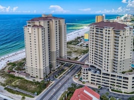 A high-rise hotel with multiple floors, a beach view, and a parking garage.