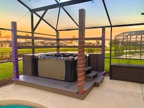 Banheira de hidromassagem sob um terraço coberto, com vista para uma área residencial.
