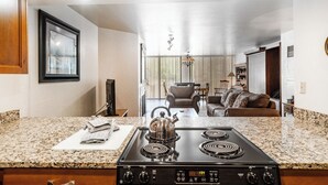 Una cucina con piani di lavoro in granito, un fornello a gas e un bollitore. Si nota una zona pranzo con una sedia e un tavolo sullo sfondo.