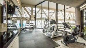Una palestra con tapis roulant, cyclette ellittiche e un espositore per manubri.