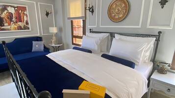 A hotel room with a large bed, a blue sofa, a small table, and a decorative wall piece.