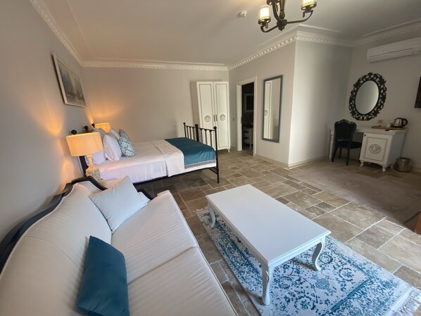 A hotel room with a bed, a sofa, a small table, a desk, and a mirror. - Villa Ephesus Hotel - Adult Only  (Kusadasi)