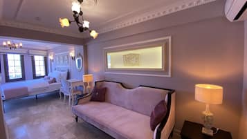 A spacious room with a large bed, a sofa, a desk, and a chandelier.