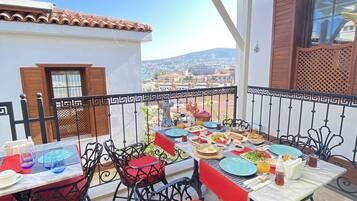 Un espace de restauration en plein air avec des tables et des chaises, une vue sur la ville et un sol carrelé.
