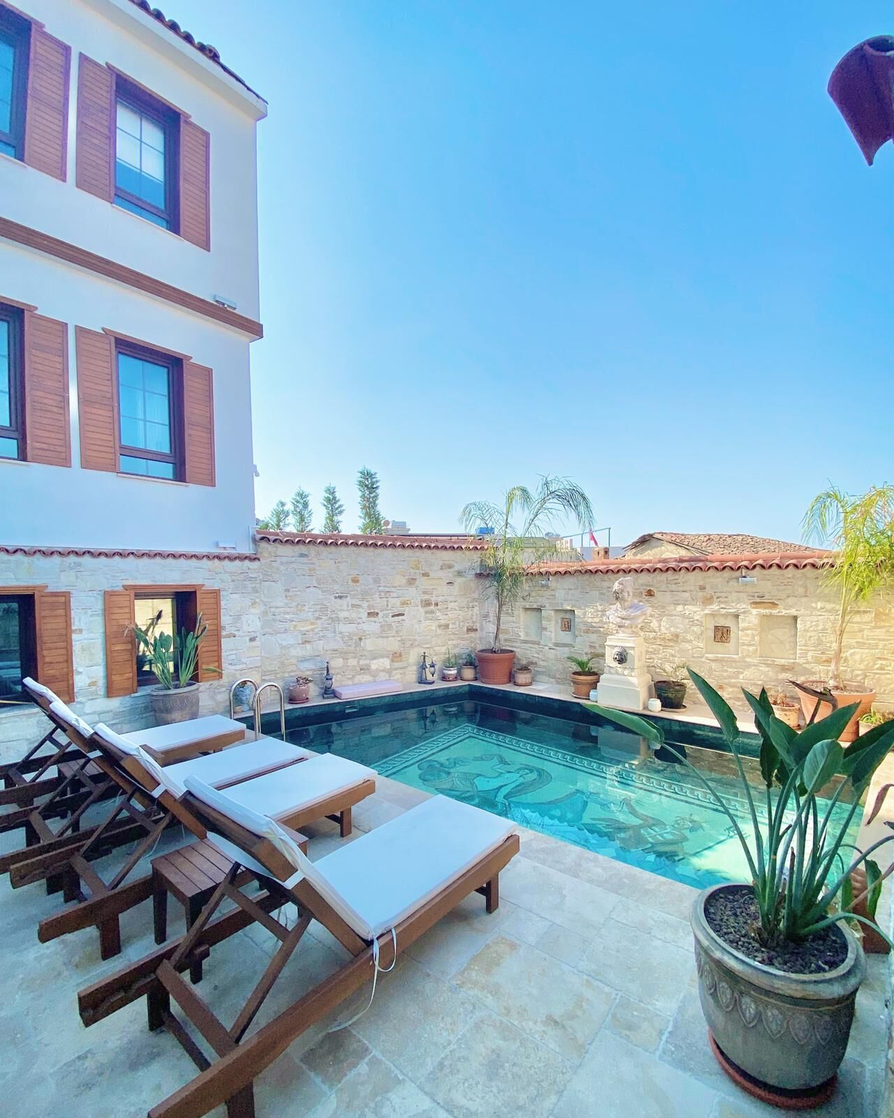 A pool area with lounge chairs and potted plants.