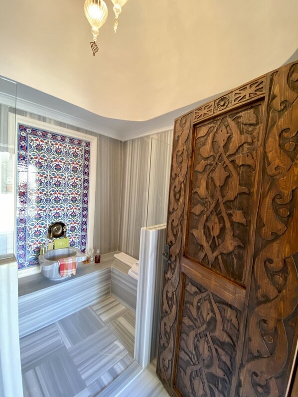 A bathroom with a patterned tile backsplash, a sink with a towel, and a wooden door with intricate carvings. - Villa Ephesus Hotel - Adult Only  (Kusadasi)