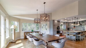A spacious kitchen with modern appliances, a large dining table, and a view of the outdoors.