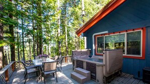 A deck with a table and chairs, a hot tub, and a small staircase leading to a covered area.