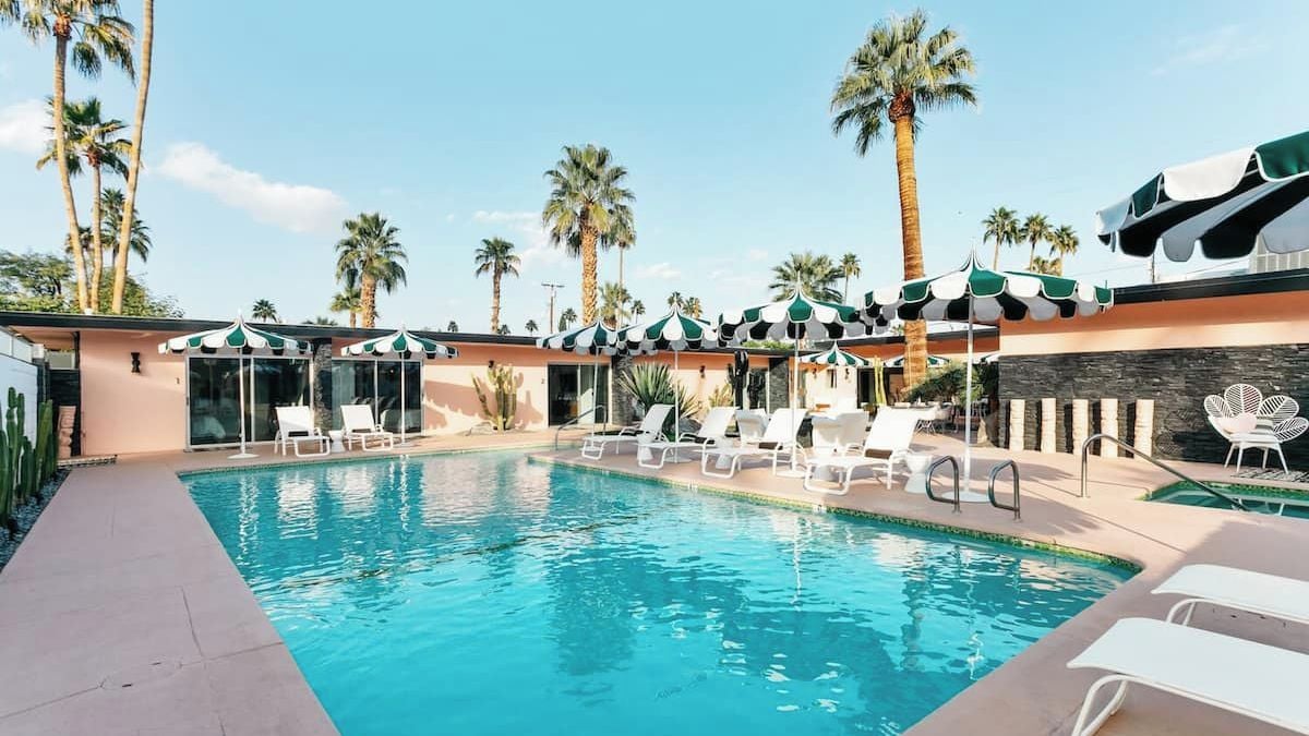 A swimming pool with lounge chairs and palm trees.