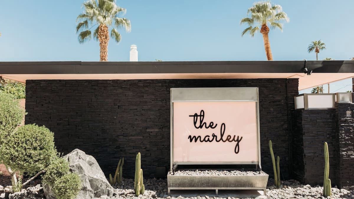 A building with a dark brick facade, a sign with 'the marley' text, and cacti in the foreground.