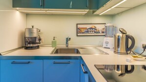 A modern kitchen with teal cabinets, a coffee machine, a kettle, and a blender.
