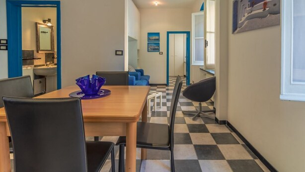 A dining area with a checkered floor, a wooden table, black chairs, and a blue vase.