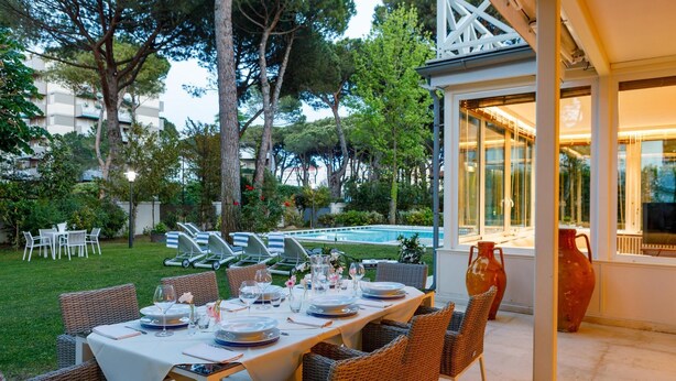 Un espace extérieur aménagé pour les repas, avec une piscine, des meubles en osier et une vue sur la piscine.