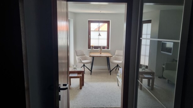 A room with a dining table, two chairs, a radiator, and a television on the wall.