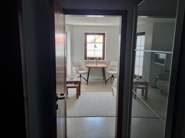 Quarto com uma mesa de jantar, duas cadeiras, um radiador e uma televisão na parede.