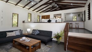 Een moderne woonkamer met een bank, salontafel en een keuken op de achtergrond.
