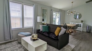 A modern living room with a sofa, a coffee table, and a dining area with a table and chairs. - Contemporary 2 Bedroom Close to Downtown, Dining (Eugene)