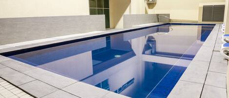 Una piscina con una solería azulejada y un interior azul.
