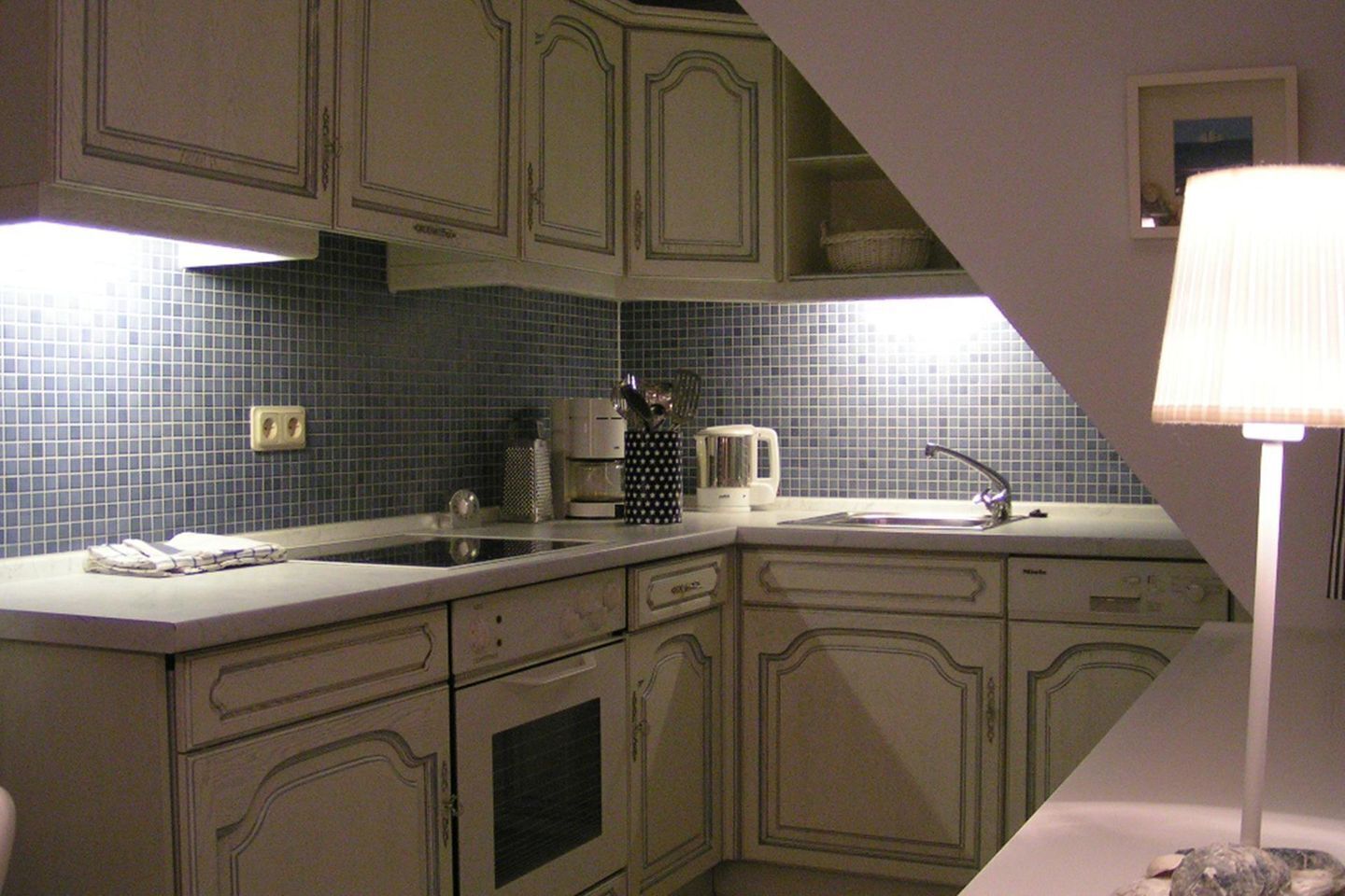 A kitchen with a sink, stove, and cabinets.