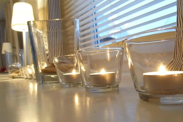 Quatre bougies allumées dans des bougeoirs en verre transparent, posées sur une table.