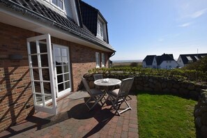 Et murstenshus med en patio, en stenvæg og udsigt til andre huse.