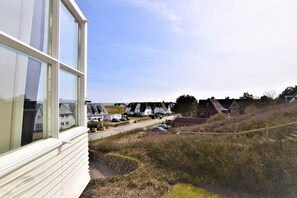 Un village côtier avec des maisons traditionnelles, une route pavée et une zone herbeuse délimitée par une clôture.