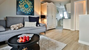 Una sala de estar moderna con un sofá gris, una mesa de centro con manzanas y un cuadro en la pared.