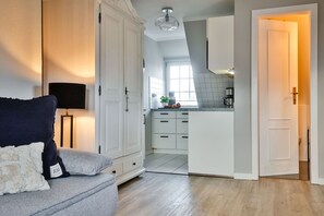 En moderne stue med en grå sofa, en sort gulvlampe og et hvidt skab.