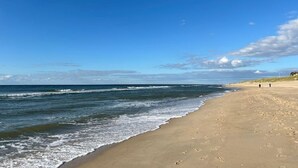 A beach with a clear sky, ocean waves, and footprints on the sand.