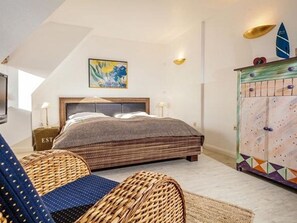 Un dormitorio con una cama, un aparador, un cuadro y una ventana.