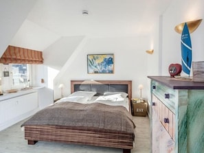 Een slaapkamer met een groot bed, een kapstok, een wandlamp en een surfboard decoratie.