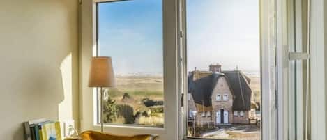 A room with a window view of a house and a landscape.