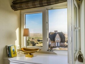 Una habitación con vista al exterior, mostrando una casa y un paisaje.