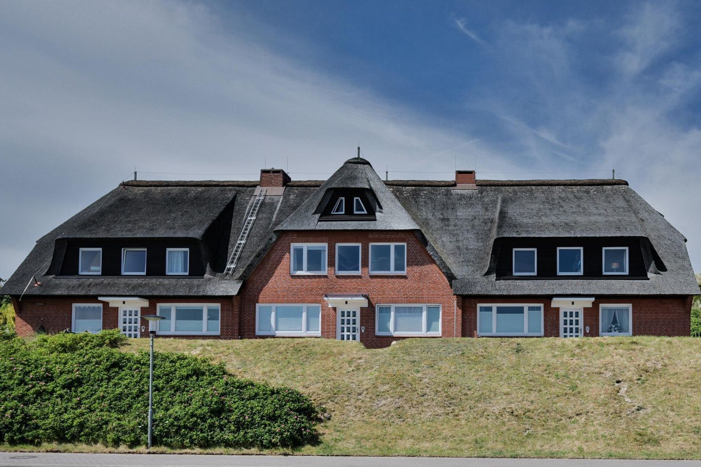A large, two-story house with a steeply pitched roof, multiple windows, and a central chimney.
