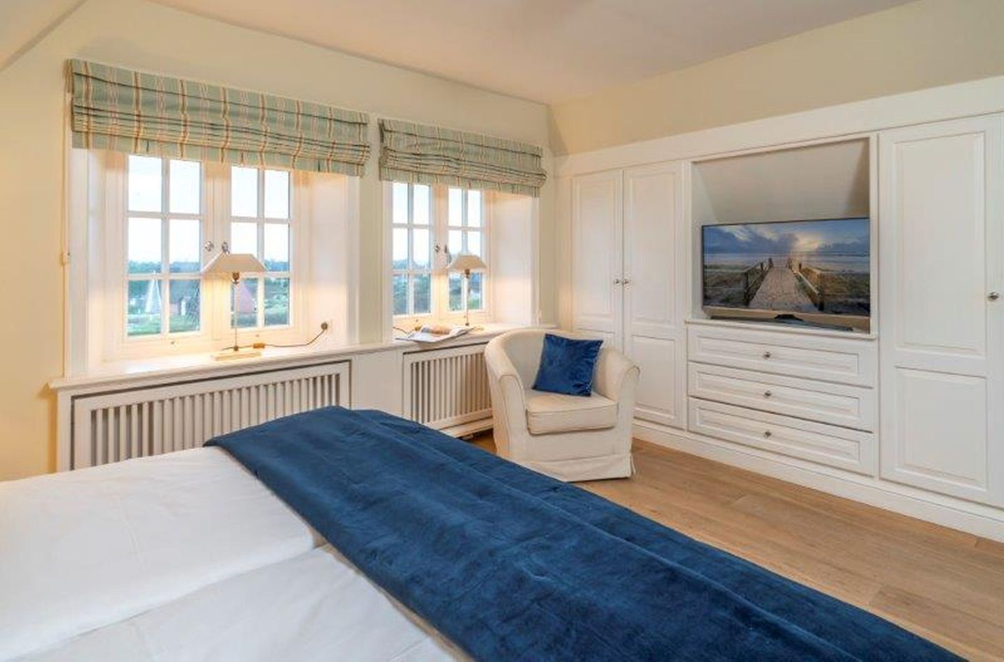 Une chambre à coucher avec un lit, une chaise, un bureau, une télévision et une vue sur la mer.