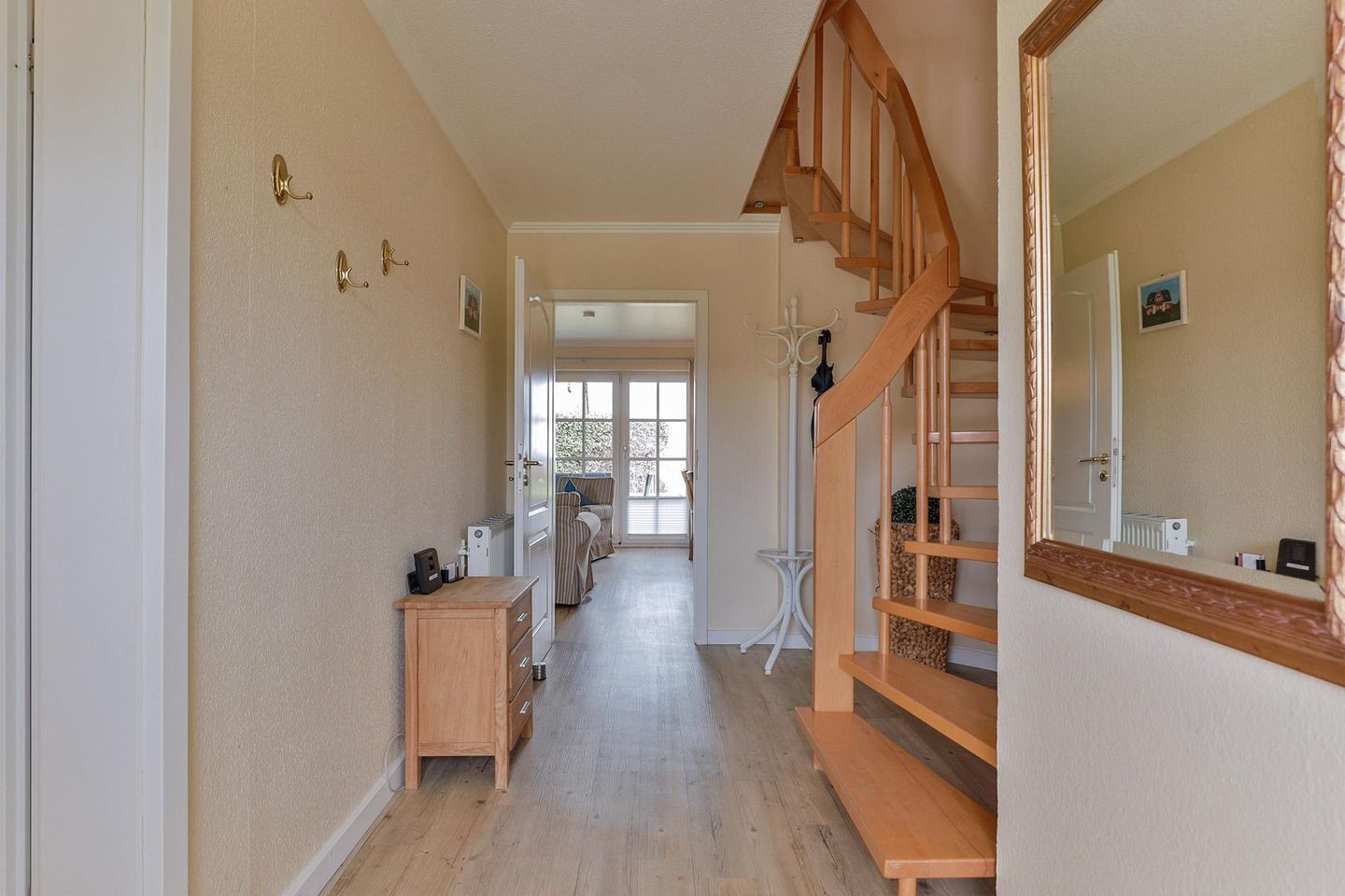 Ein Flur mit einer Holztreppe, einem Holztisch und einem großen Spiegel.