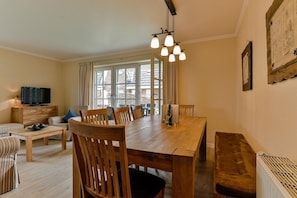 A cozy living room with a wooden dining table, chairs, a sofa, and a TV. - House on the Watt - House on the Watt DO/05b (Sylt)