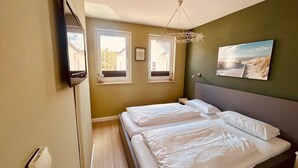 A bedroom with two beds, a large window, and a painting on the wall. - Im Dünengrund "Rebinka" DUE/01 - Apartment 02 - Dünengrund (Sylt)