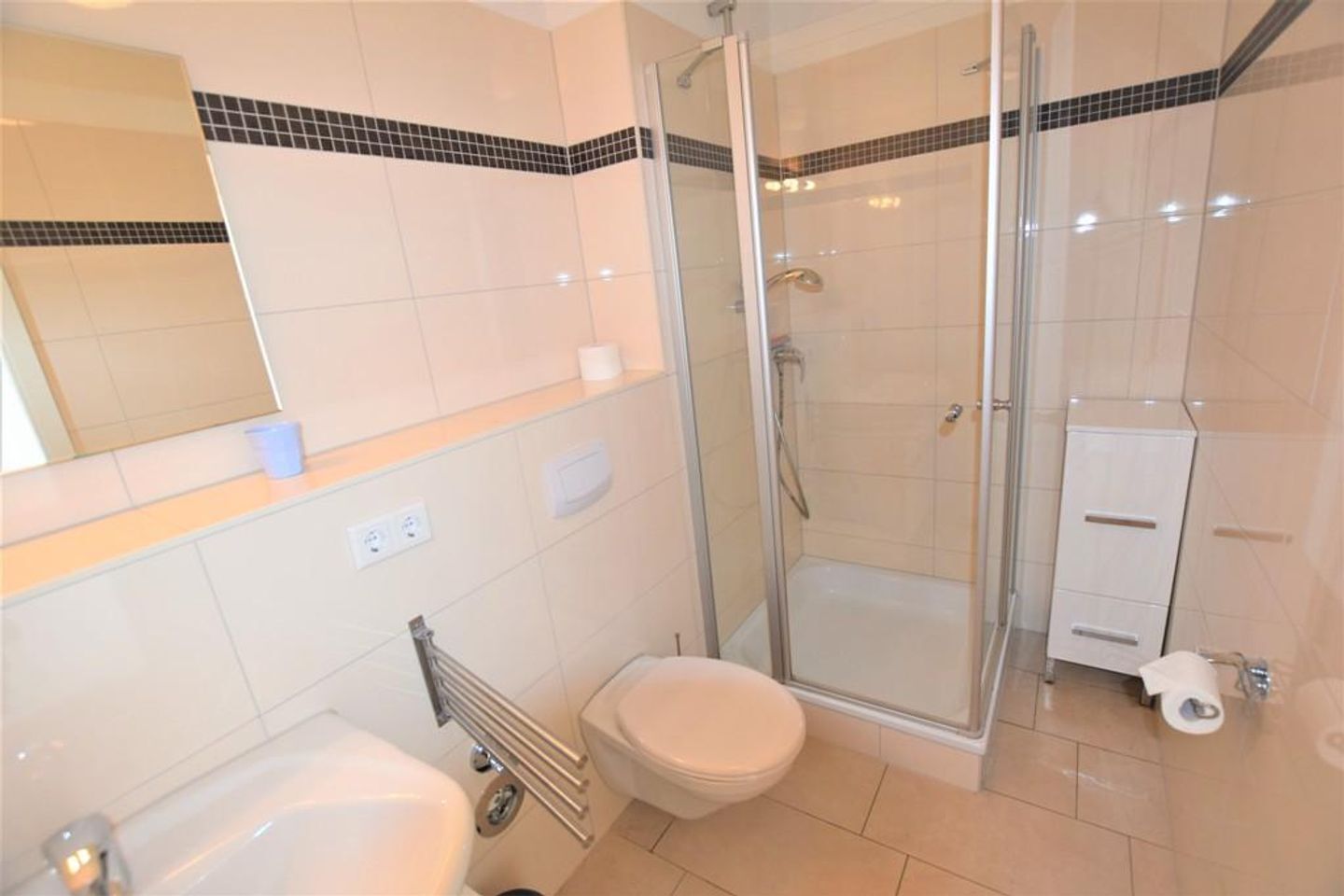 A bathroom with a glass-enclosed shower, a toilet, and a sink.