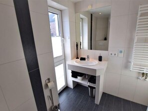 A modern bathroom with a white sink, mirror, and towel rack. - House Dünenblick DUE/12 - Dünengrund (Sylt)