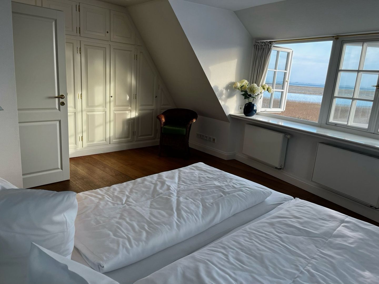 A bedroom with a bed, a window with a view, and a chair.