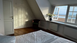 A bedroom with a bed, a window with a view, and a chair.