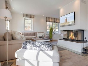 A modern living room with a fireplace, a sofa, a coffee table, and a large window.