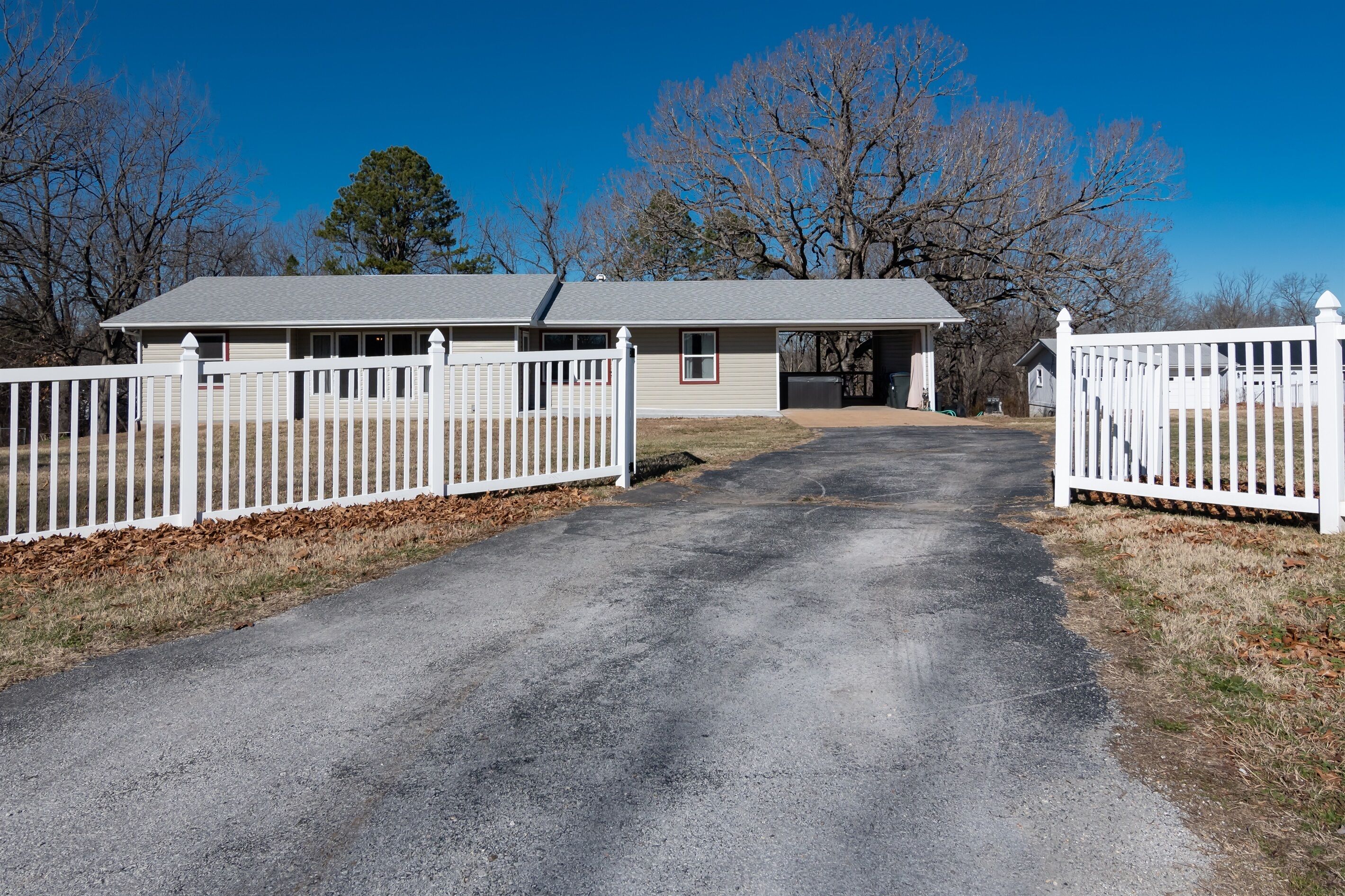 A two-story house with a driveway leading to a gated entrance.