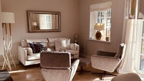 A living room with a white sofa, two armchairs, a coffee table, and a large mirror on the wall. - "Raanwaikoje" RA/14B - Raanwaikoje (Sylt)