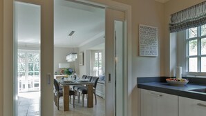 A modern kitchen with a dining area, a large window, and a view of the outdoors. - "Raanwaikoje" RA/14B - Raanwaikoje (Sylt)