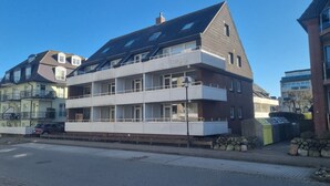 Un immeuble résidentiel à plusieurs étages, doté de balcons et d’un toit plat.