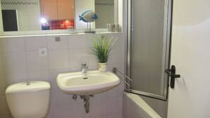 Une salle de bain avec des toilettes, un lavabo et une douche.