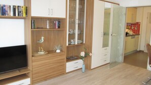 Un salon doté d’un téléviseur à écran plat, de meubles en bois, d’une vitrine et d’un coin repas avec un mur recouvert de carreaux rouges.